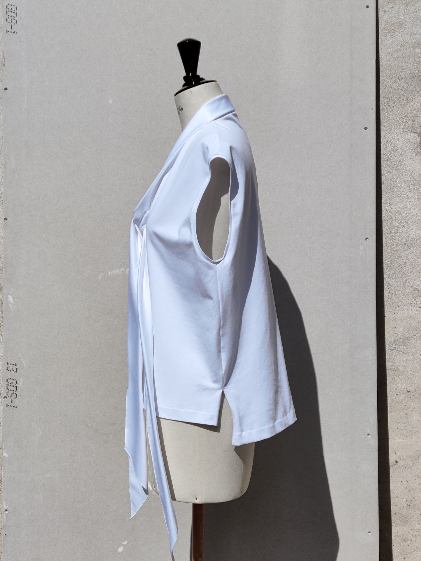 Side view. The Aryna shirt (white) has spilt side seams cut in the cotton shirt quality with the back hemline being longer than the front.