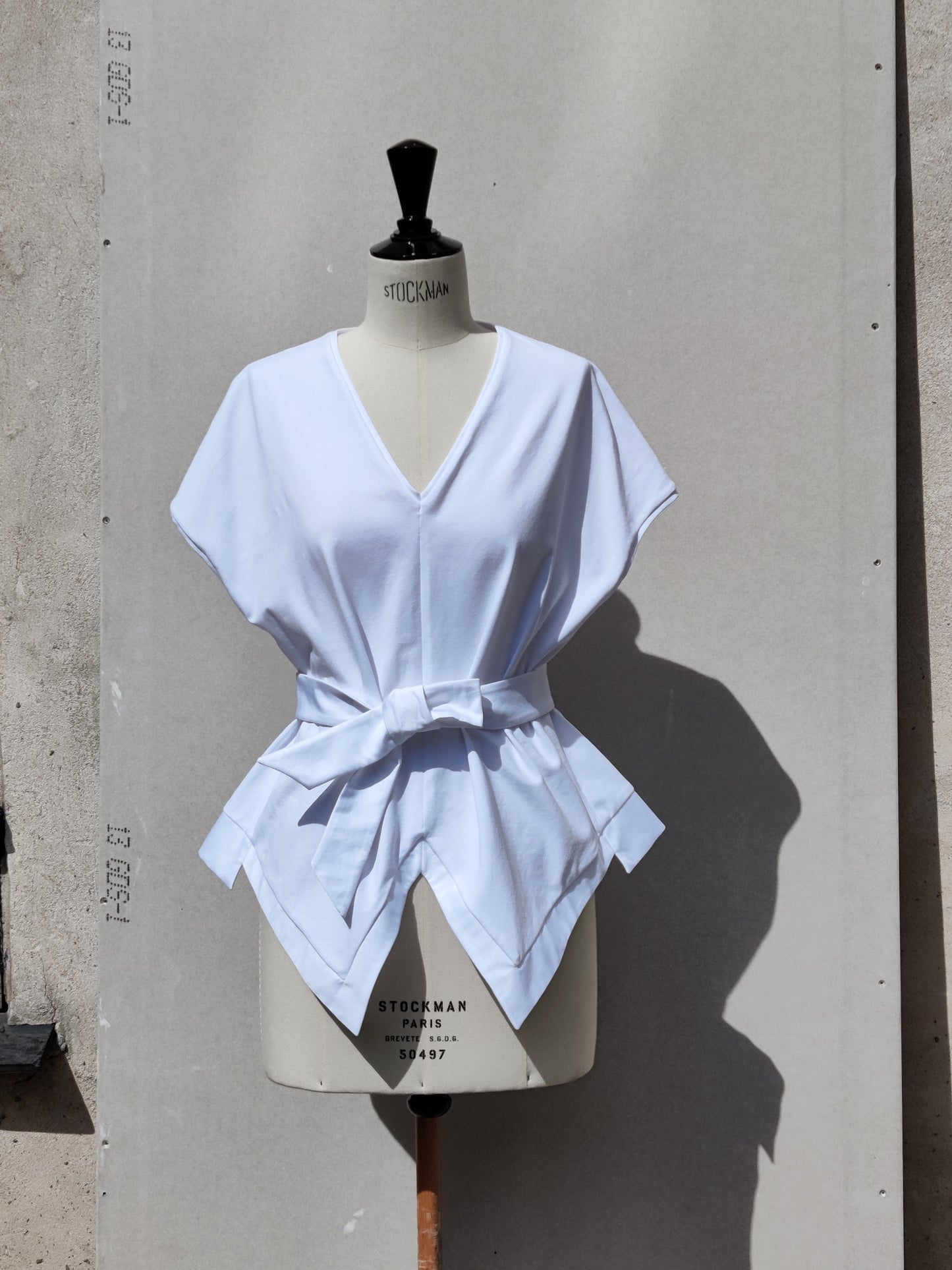 Front view. The Aider top has a V-neck and additional fabric inserts in sides, also with added cotton detail on the hem. Aider comes with a cotton belt, which can be used to emphasis the waist.