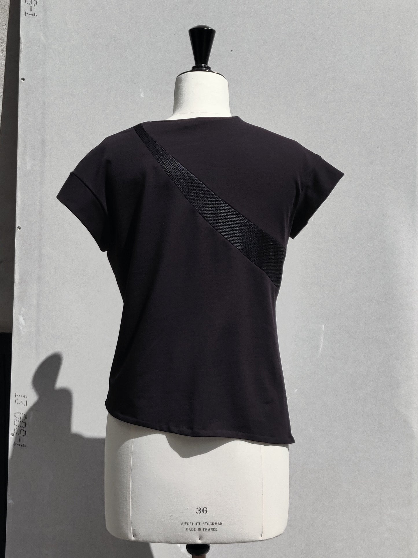 Back view. The Ashlee T-shirt has a cut-out lined mesh detail on the front and a different cut-out lined mesh detail on the back.