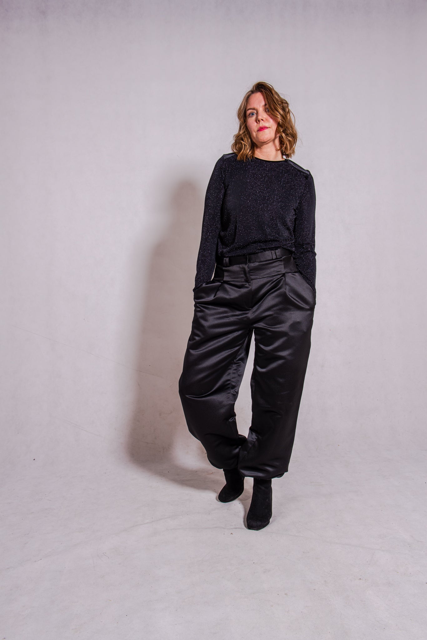 Woman wearing black Ailo top (stripey) with Agnes trousers in black.