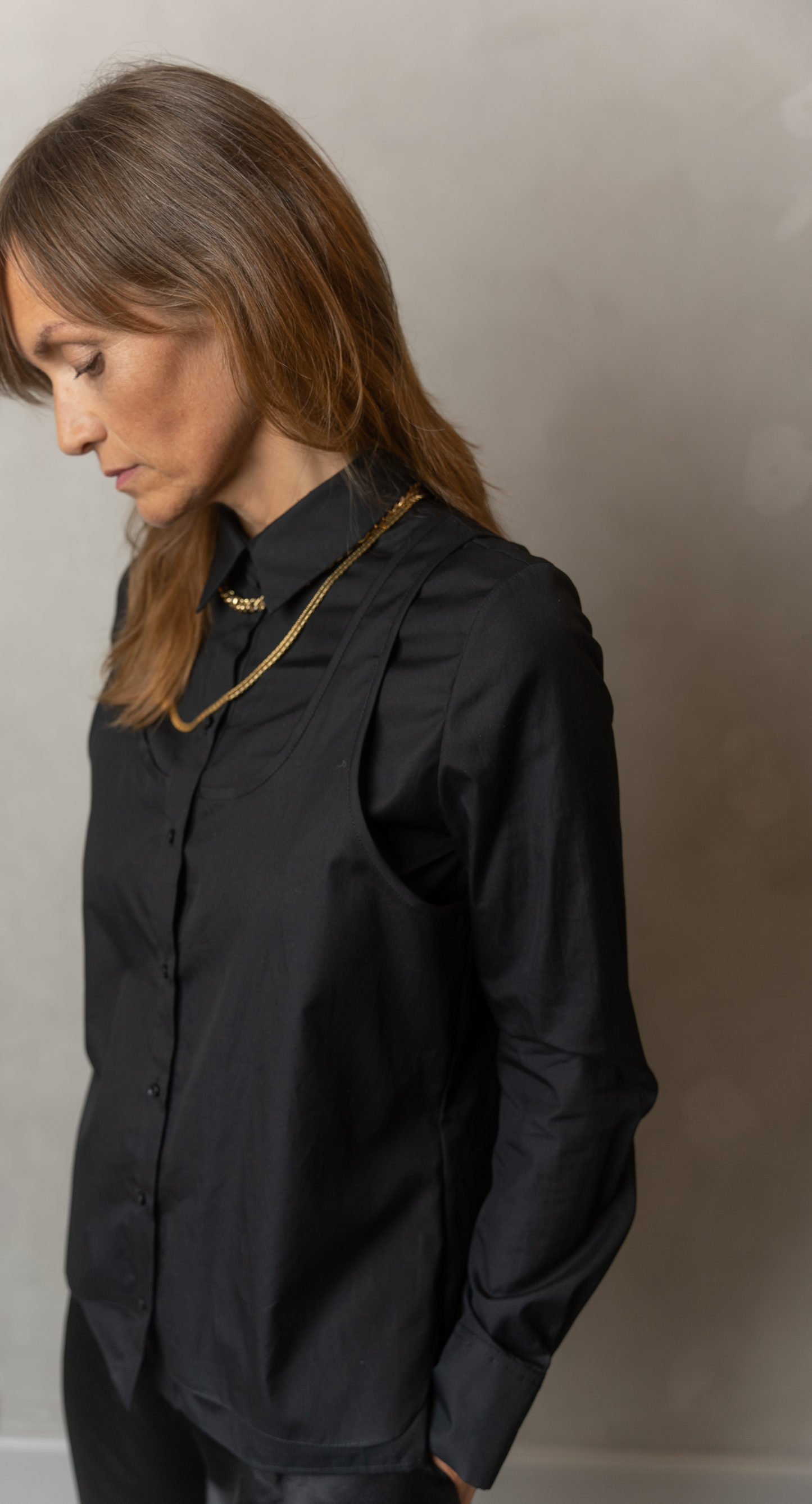 Women wearing Abbey shirt black paired with Agnes trousers (black) looking down..