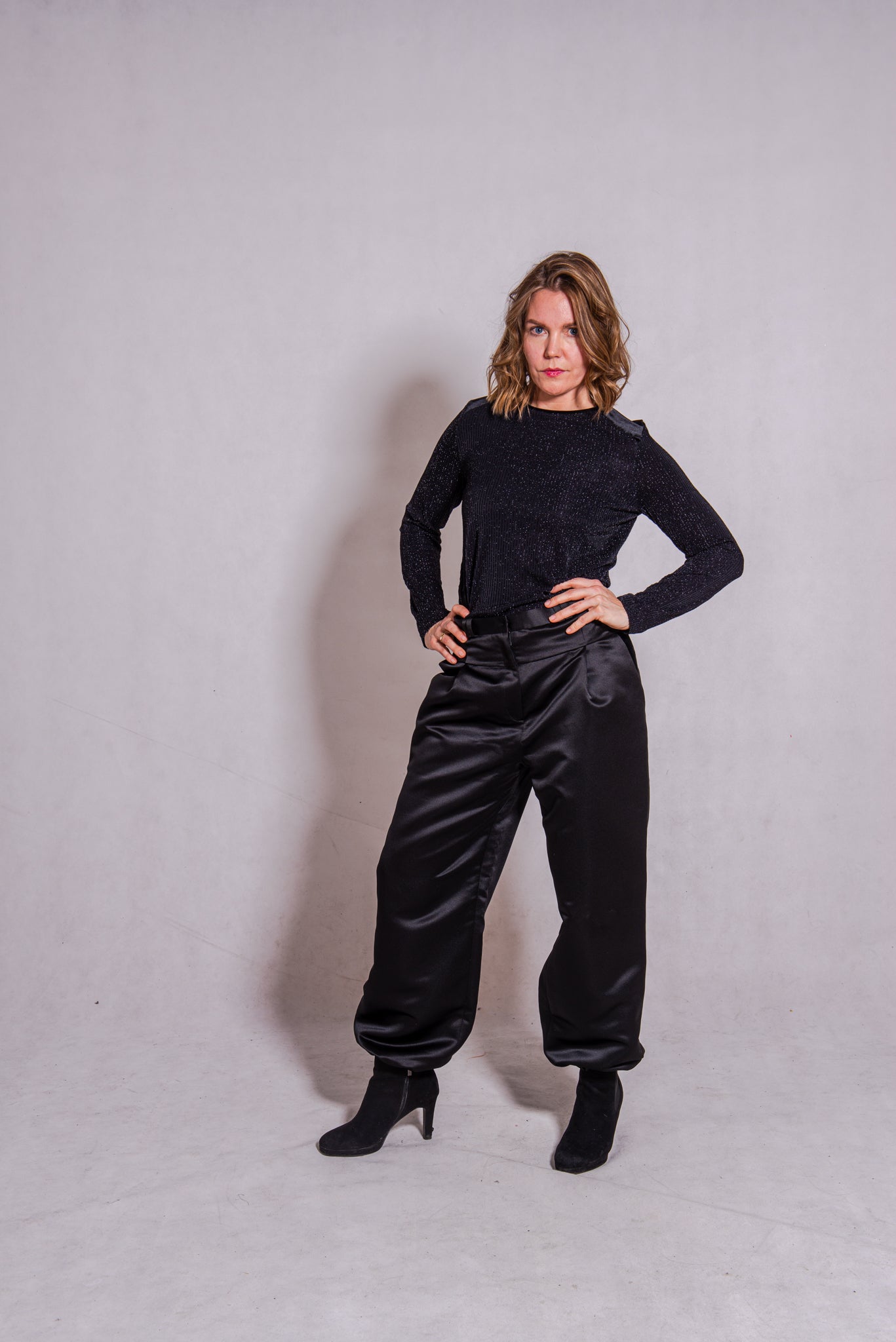 Woman wearing black Ailo top (stripey) with Agnes trousers in black.