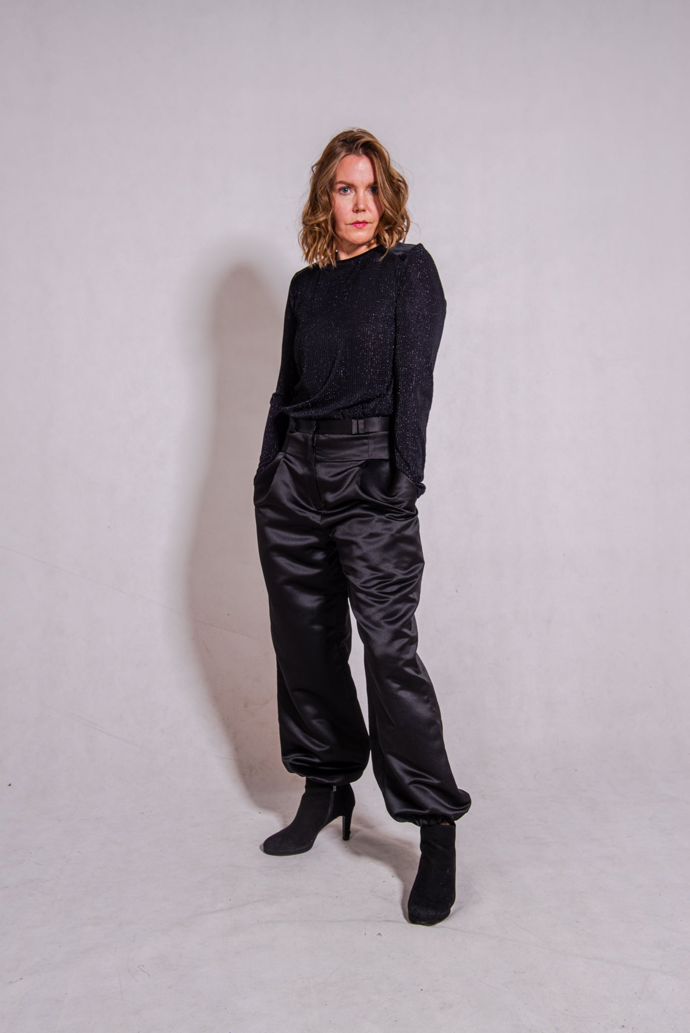 Woman wearing black Ailo top (stripey) with Agnes trousers in black.
