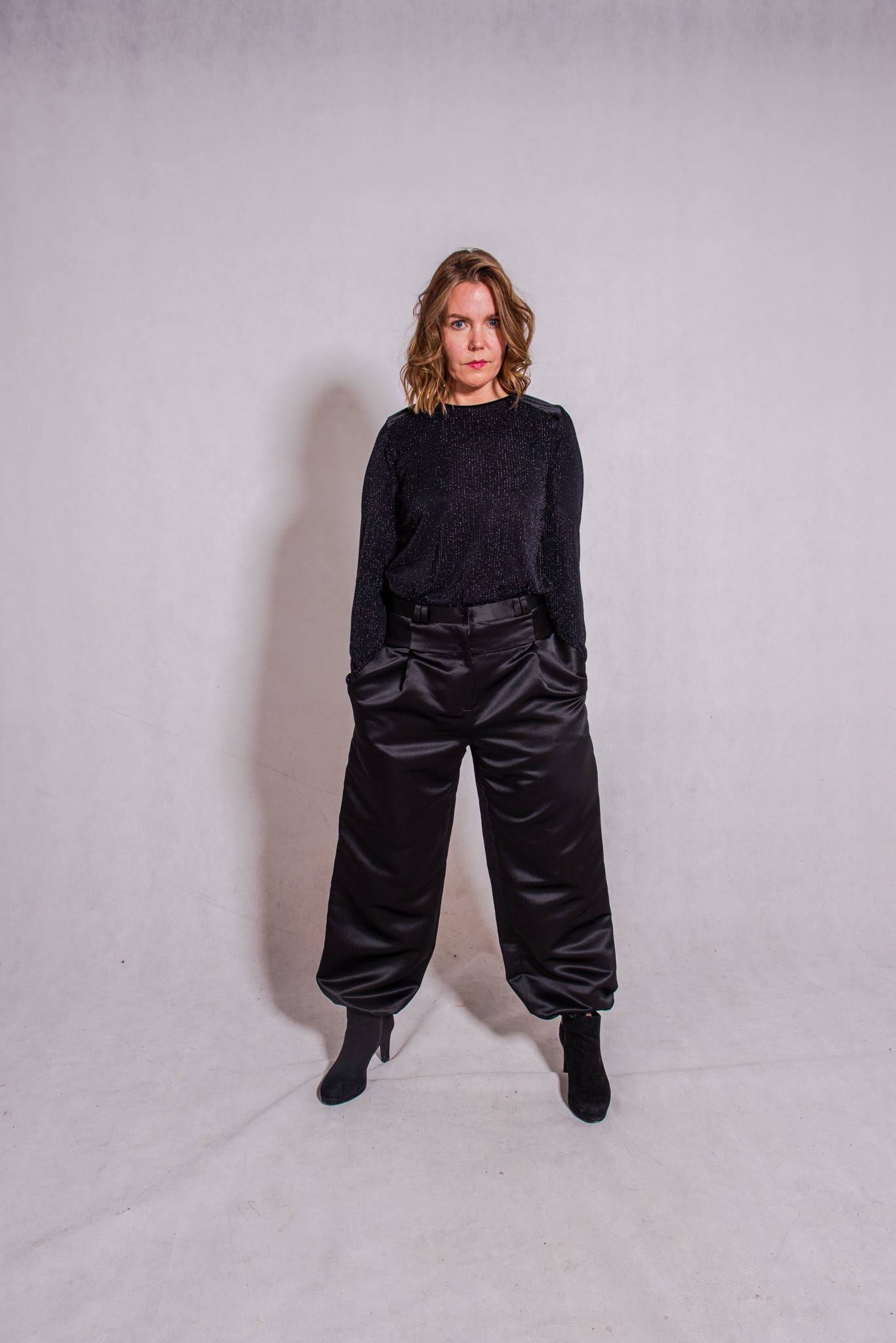 Woman wearing black Ailo top (stripey) with Agnes trousers in black.