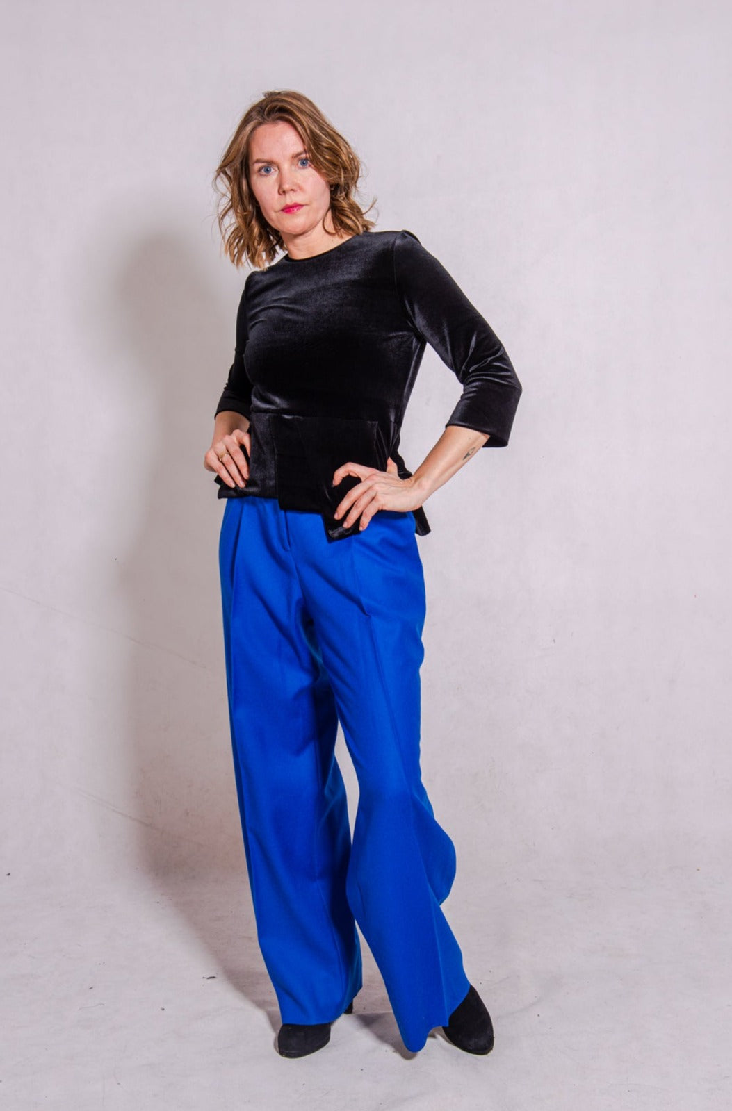 Model looking direct wearing Ann-Marie top, black, & Ava trousers, blue wool.