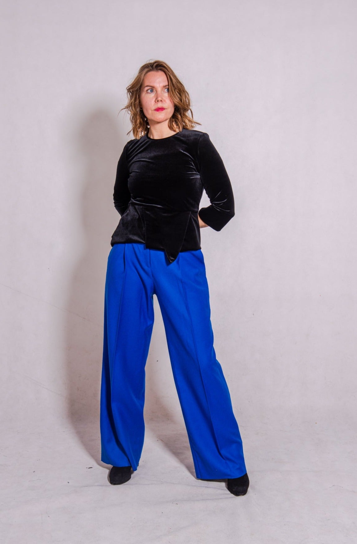 Model looking up wearing Ann-Marie top, black, & Ava trousers, blue wool.