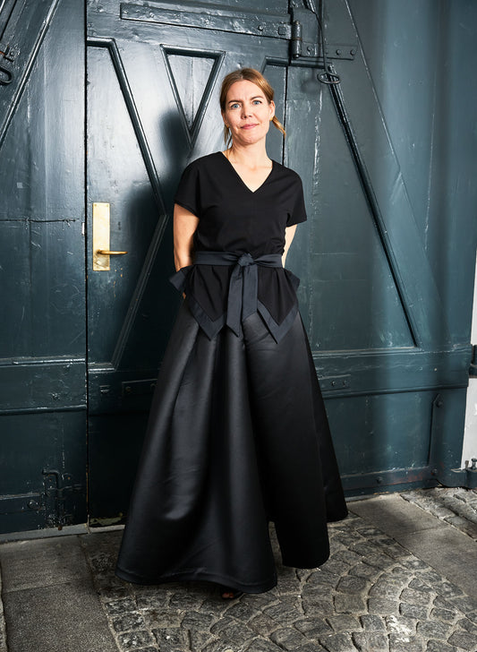 Woman wearing Aider blouse (lack) with our Alayan skirt.